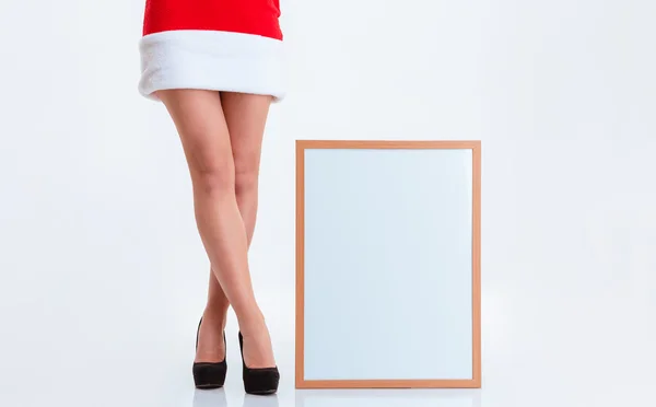 Sexy pernas femininas em pano de santa claus e placa em branco — Fotografia de Stock
