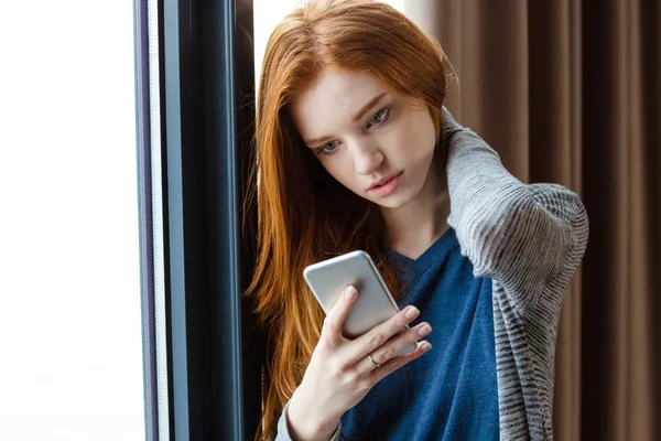 Attraktive Dame mit Handy am Fenster — Stockfoto