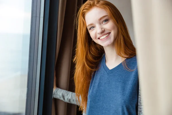 Veselá hezká dívka s červenými vlasy pohledu kamery a s úsměvem — Stock fotografie