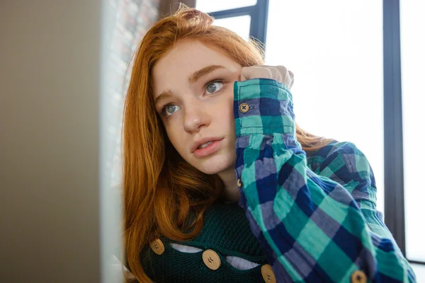 Concentrated woman with red hair hugging knitted cushion — Stock Photo, Image