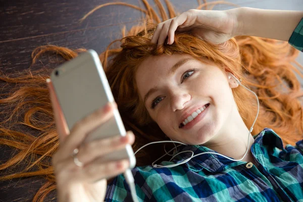 Wesoły pozytywny rudy kobieta słuchanie muzyki i uśmiechając się — Zdjęcie stockowe