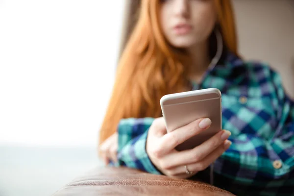 Closeup of cellphone is used by pensive young redhead woman — Stock Photo, Image