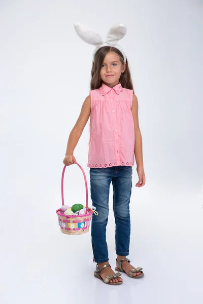 Little girl with rabbit ears holding basket of eggs — Stock Photo, Image