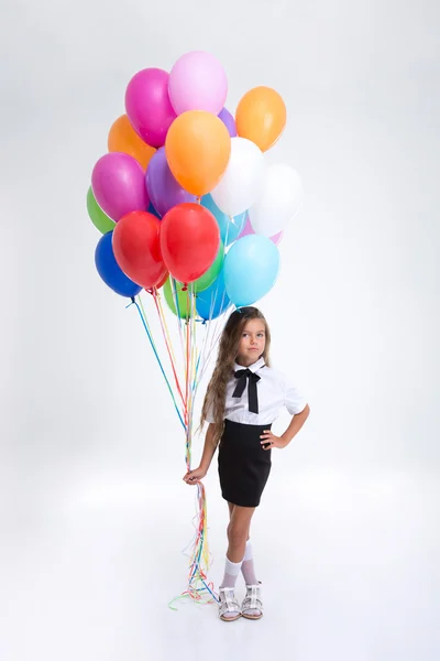 Ganska liten skolflicka står med ballonger — Stockfoto