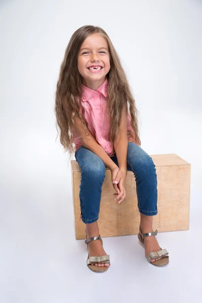 Retrato de uma menina feliz sentada na caixa de madeira — Fotografia de Stock