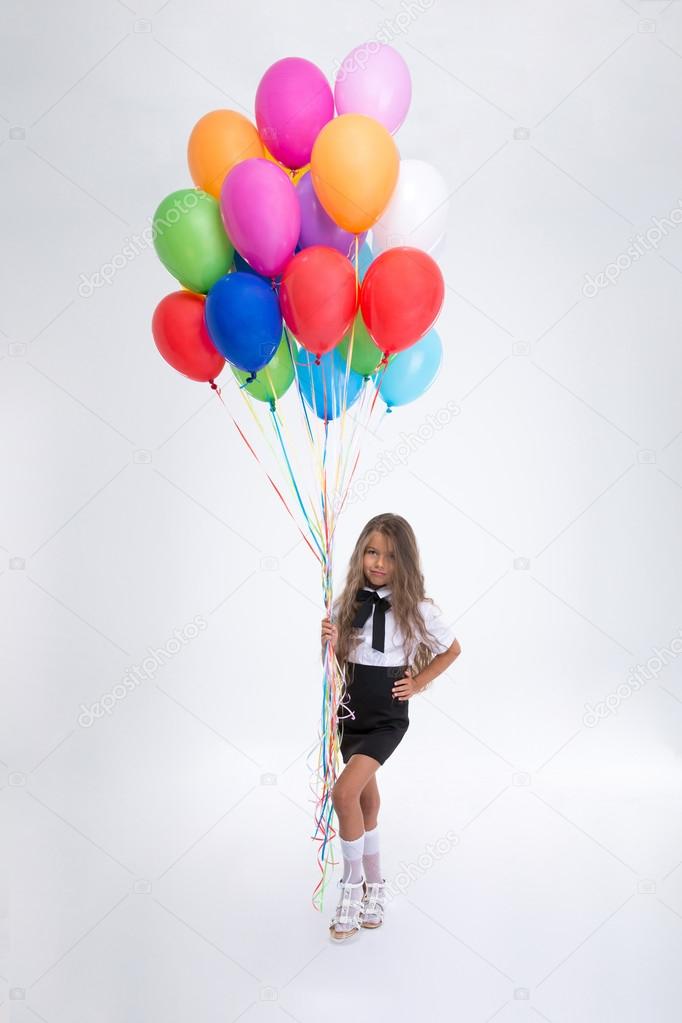 Cute little school girl standing with balloons