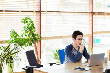 Dizüstü bilgisayar Office ile çalışan Asyalı adam konsantre