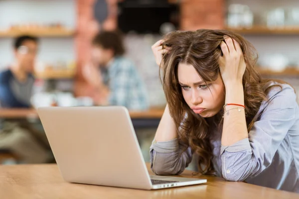 Exhausted stressed young woman with tousled hair using laptop — Stock Photo, Image