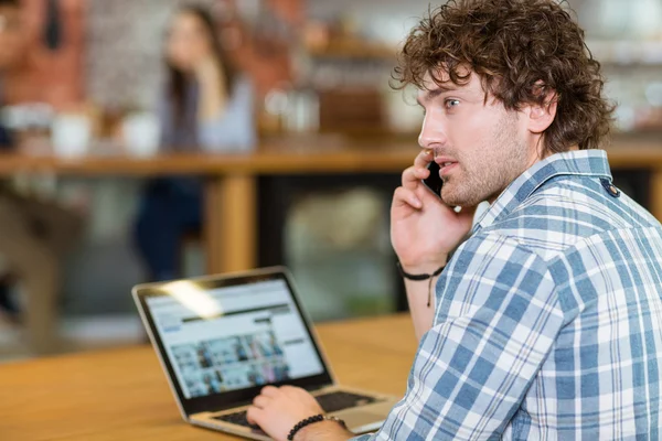 Vue arrière de l'homme en utilisant laptope et smartphone — Photo