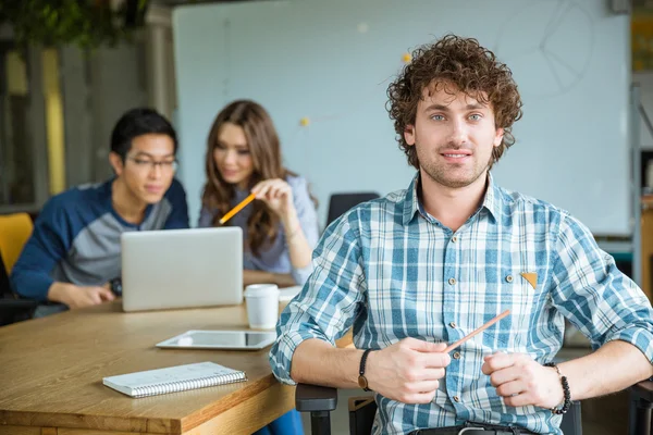 Atractivo alegre joven rizado malestudying con los estudiantes en el aula — Foto de Stock