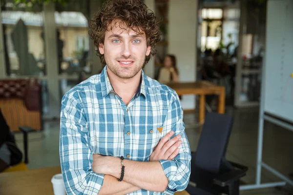 Handsome attractive cheerful young curly man with arms crossed — Stock Photo, Image