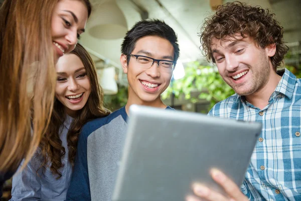 Glada unga människor skrattar och använder tablet — Stockfoto