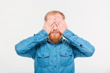 Young handsome blond bearded male with eyes covered by hands