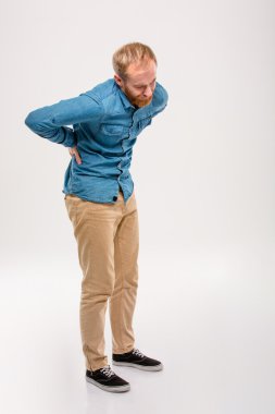 Full length portrait of young bearded man having back pain