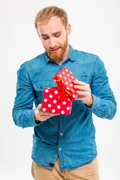 Excited male with beard in jeans shirt opening gift — Zdjęcie stockowe