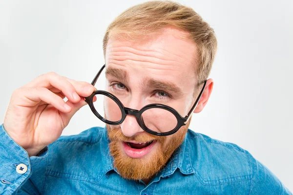Amusing happy man with beard looking over his round glasses — Stockfoto