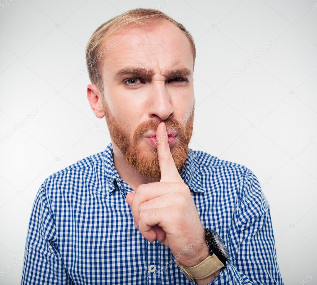 Young casual man showing finger over lips