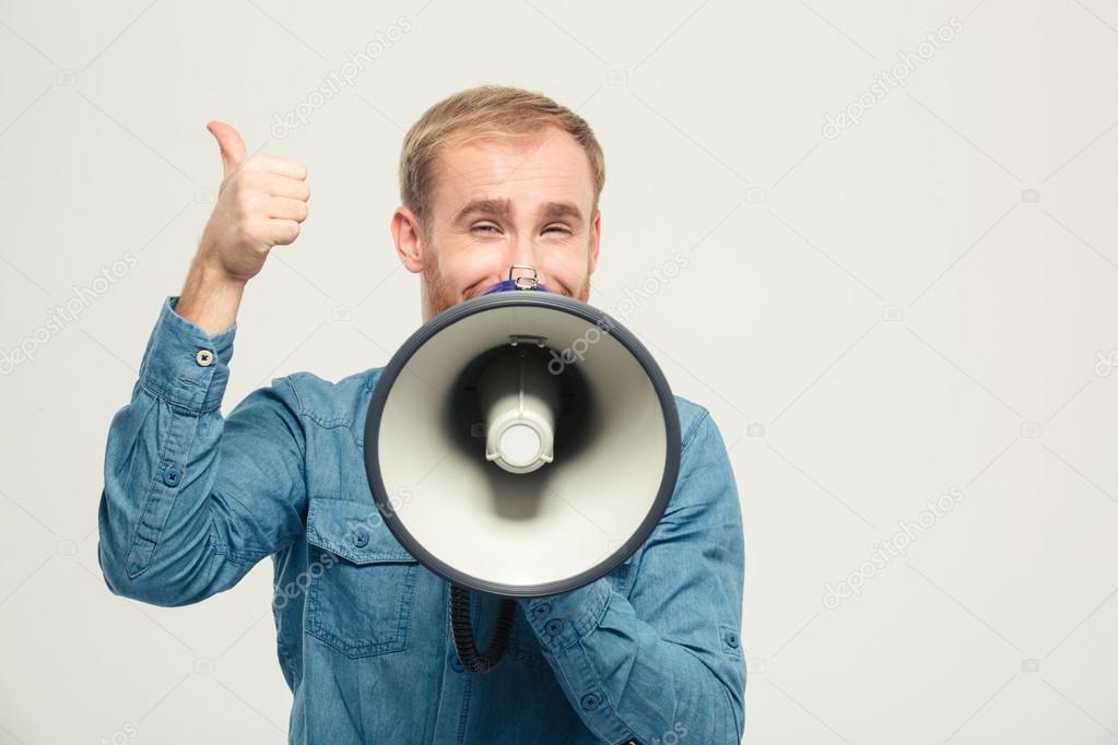 Happy man with megaphone showing thumb up