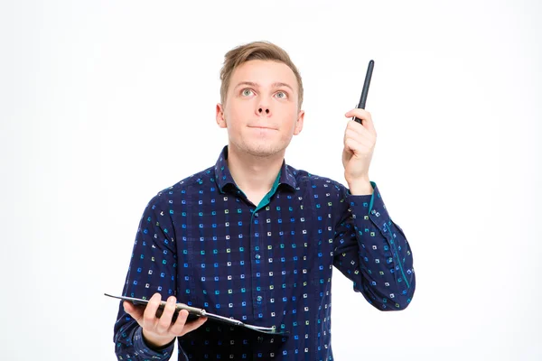 Concentrated handsome man holding clipboard and pointing up by pen — Stockfoto