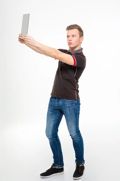 Amusing concentrated young man making selfie using tablet — Stock Photo, Image