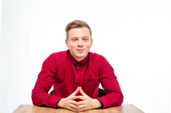 Inhoud knappe jongeman in rode shirt zitten en glimlachen — Stockfoto