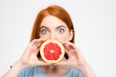 Shocked amusing lady holding grapefruit half in front of mouth 