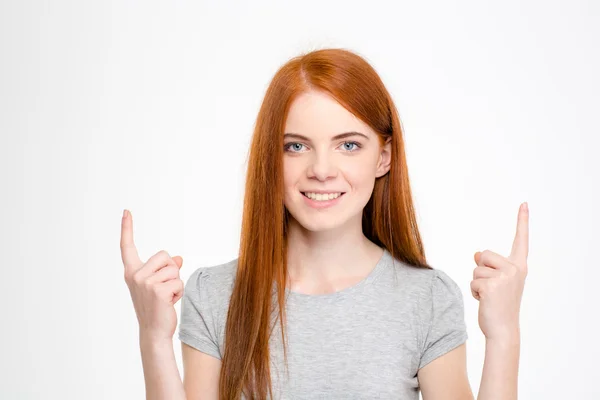 Happy cheerful redhead young woman with long hair pointing up — Stockfoto