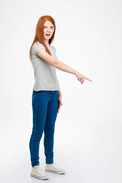 Surprised attractive young woman with opened mouth pointing down — Stock Photo, Image