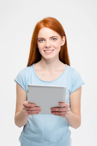 Pretty smiling redhead lady with long hair using tablet isolated — Stok fotoğraf