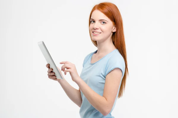 Hermosa mujer joven alegre sosteniendo y usando tableta — Foto de Stock