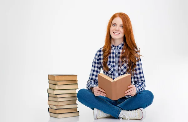 Donna ispirata seduta vicino pila dei libri e lettura — Foto Stock