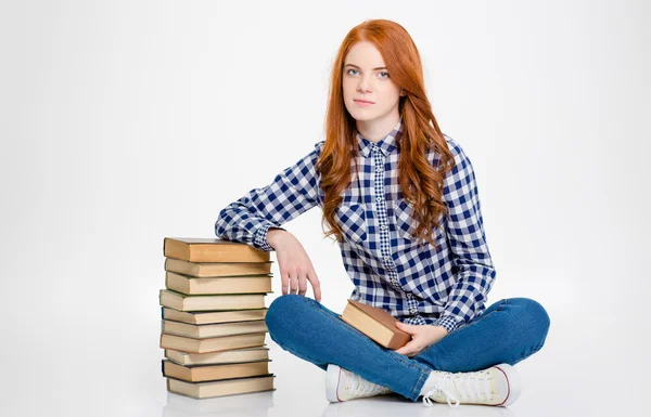 Pensif paisible jeune femme bouclée assis près de la pile de livres — Photo