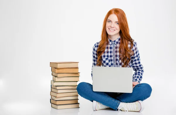 Femme heureuse assise près de la pile de livres et en utilisant un ordinateur portable — Photo