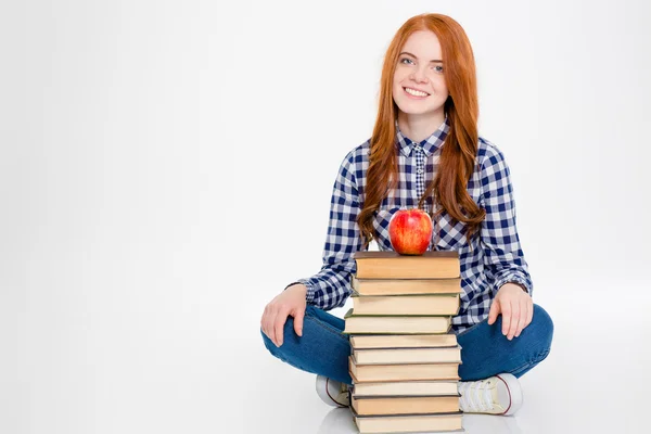Женщина сидит возле стопки книг с яблоком сверху — стоковое фото