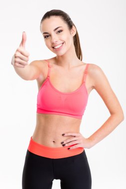 Pretty positive smiling sportswoman in tracksuit showing thumbs up 