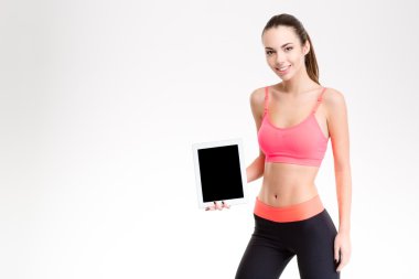 Happy cheerful young sportswoman showing tablet pc blank screen 
