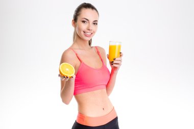 Happy fitness woman holding half of orange and  juice
