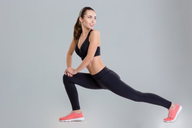 Smiling pretty young sportswoman stretching her legs and looking back
