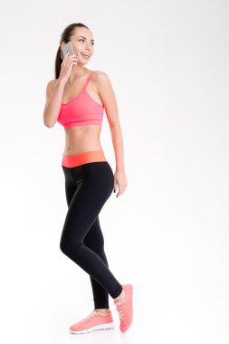 Attractive positive fitness girl talking on mobile phone