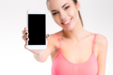 Happy pretty fitness girl showing cellphone with blank screen 