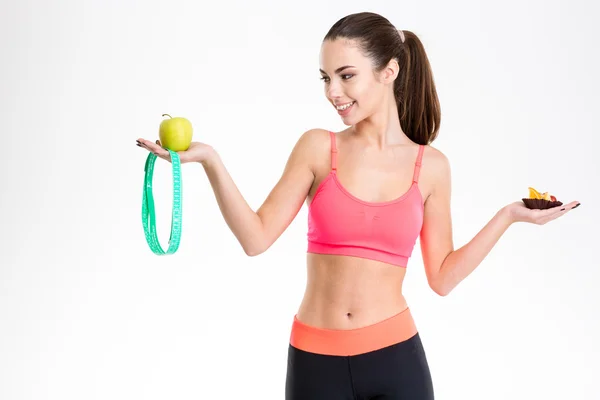 Charmante, glückliche junge Sportlerin, die sich zwischen gesunder und ungesunder Ernährung entscheidet — Stockfoto