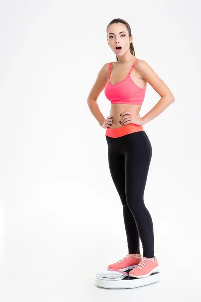 Красивая удивленная молодая фитнесс-женщина стоит на весах — стоковое фото