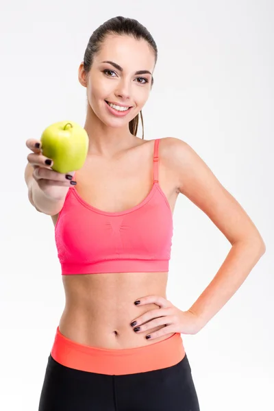 Pretty positive young sportswoman giving an apple — Stock Photo, Image