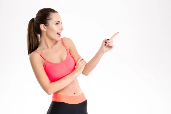 Excited content pretty fitness girl in sportwear pointing away — Stock Photo, Image