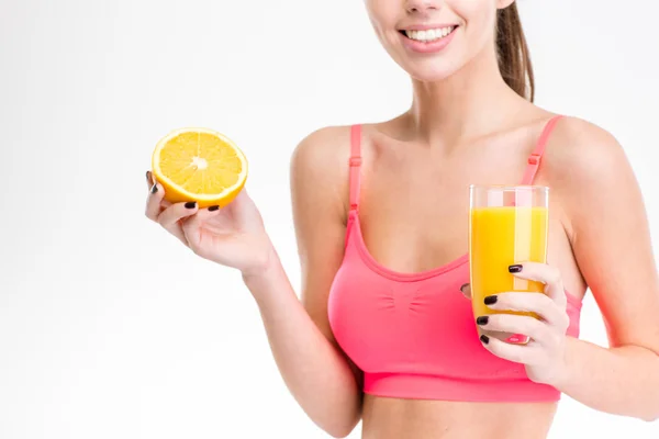 Closeup of half orange and juice holded by fitness woman — Zdjęcie stockowe