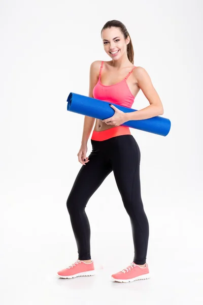 Attractive smiling young fitness woman holding yoga mat — Stok fotoğraf