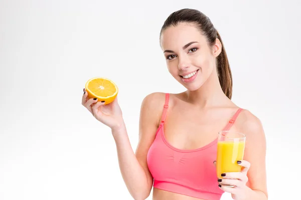 Fitness girl with orange half and glass of juice — Stockfoto