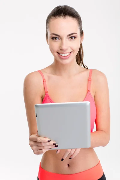 Sorrindo menina fitness bonita no topo rosa usando tablet — Fotografia de Stock