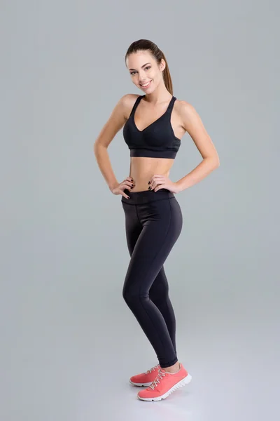 Sonriendo atractiva joven fitness mujer de pie y posando — Foto de Stock