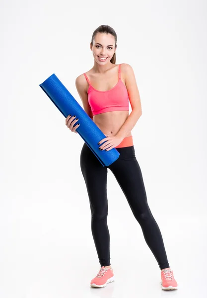 Mulher fitness feliz bonita de pé e segurando tapete de ioga — Fotografia de Stock